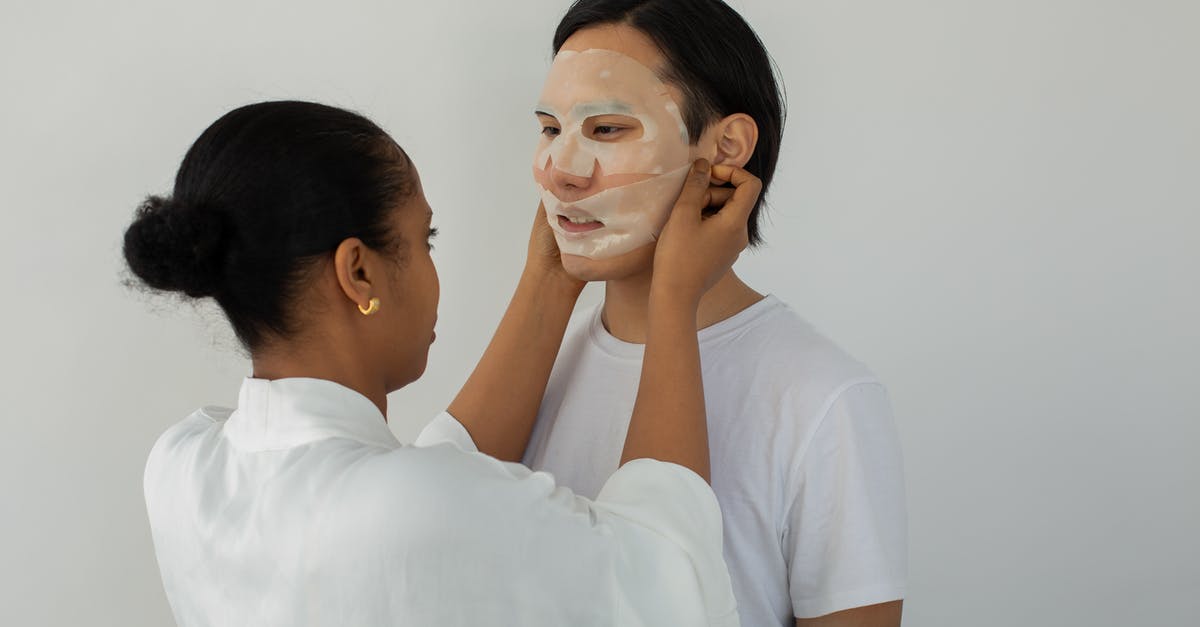 Why aren't my macarons as soft as professional ones? - African American female beautician applying moisturizing mask on face of young ethnic man while looking at each other on light background