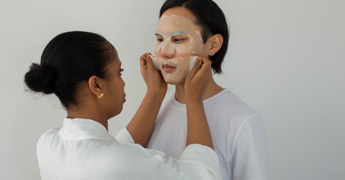 Why aren't my macarons as soft as professional ones? - Black female cosmetician applying moisturizing mask on face of ethnic man while looking at each other on light background