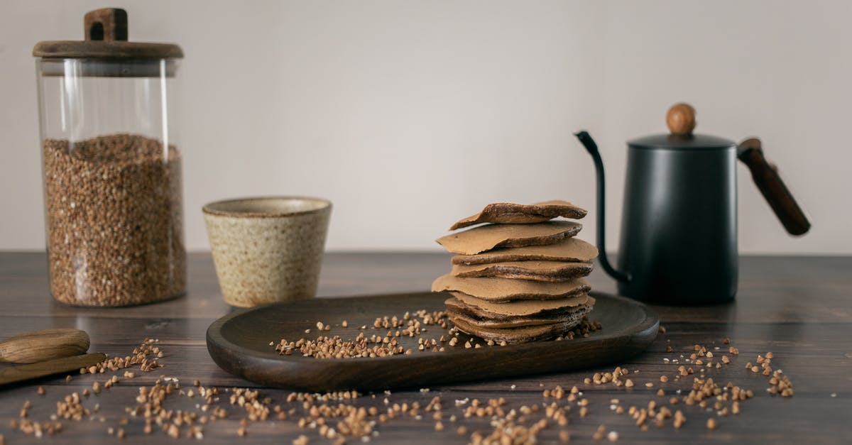 Why Buckwheat Pancakes? - Yummy buckwheat chocolate stuff pancakes served on wooden plate with glass jar of grains and kettle with cup