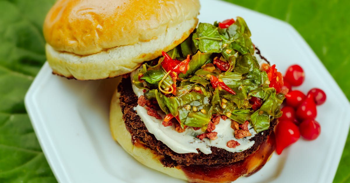 Why did my piece of beef harden on crock pot? - From above of big hamburger with dark brown fried cutlet covered with vegetables and salad dressing in daytime on blurred background