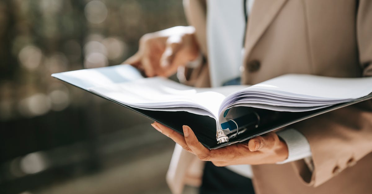 Why do bananas turn black in the refrigerator? - Crop faceless female entrepreneur in formal jacket turning pages of documents in folder while reading