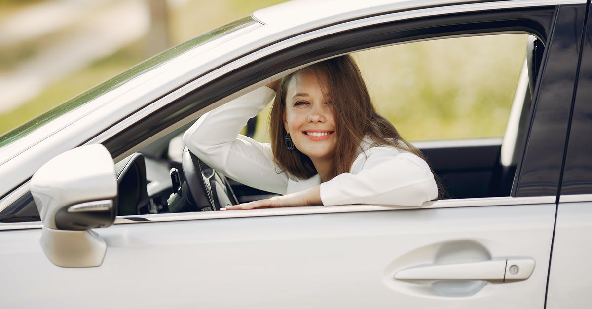 Why do hand held can openers stop working so quickly? - Cheerful female driver in white shirt sitting inside modern automobile and looking at camera through opened side window with smile during car trip in summer day