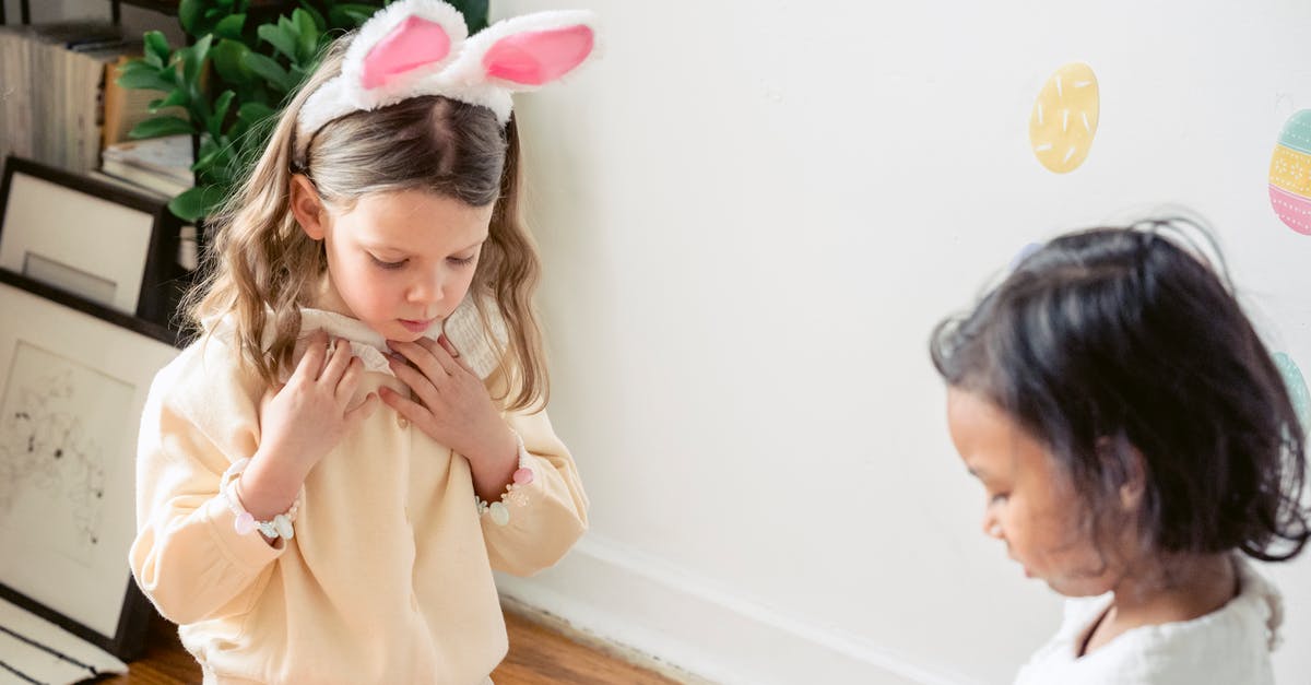 Why do most egg tart molds appear to be blackened? - Cute calm little girl with bunny ears on head sitting on floor at home and playing with ethnic friend during Easter holidays