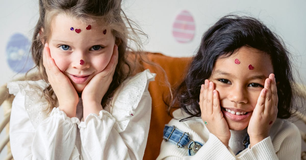 Why do most egg tart molds appear to be blackened? - Positive multiracial girls with hear shaped stickers on faces touching cheeks and looking at camera while sitting near wall with egg decorations during Easter holiday