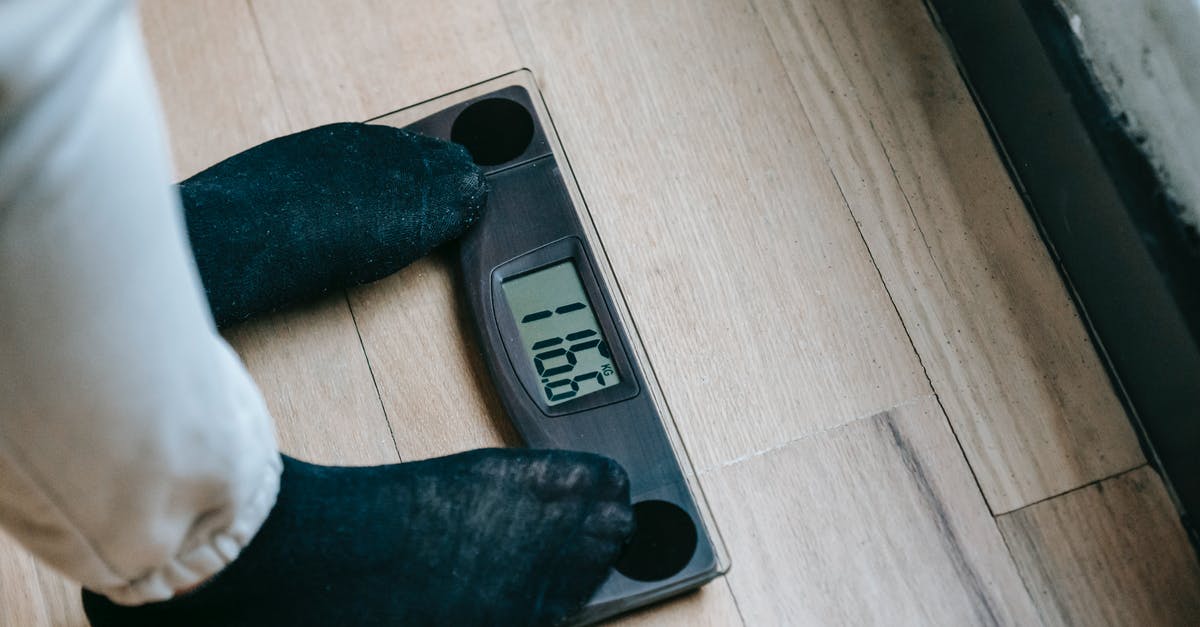 Why do my weighing scales have ml and g? - From above of unrecognizable person in socks standing on electronic weighing scales while checking weight on parquet during weight loss