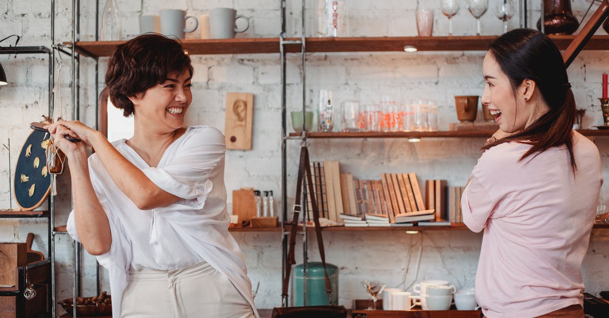 Why do store-bought dips have such a limited shelf life? - Young ethnic female buyers interacting while laughing near shelves with kitchen items and looking at each other in store