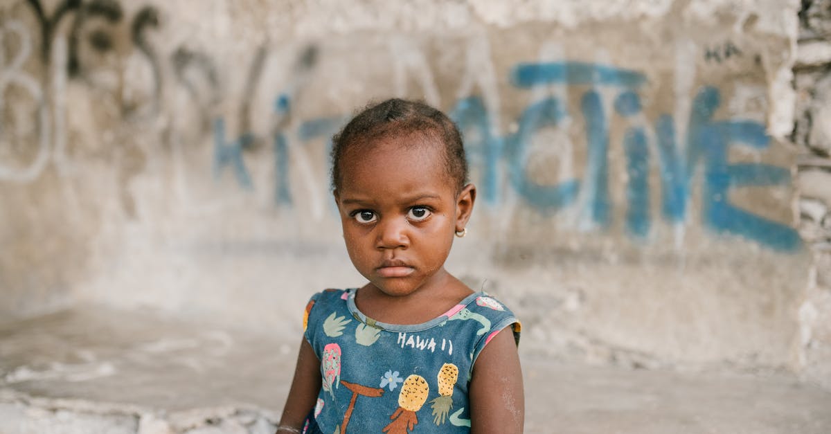 Why do we need to reheat food? - Frowning African American girl near weathered concrete building with vandal graffiti and broken wall in poor district