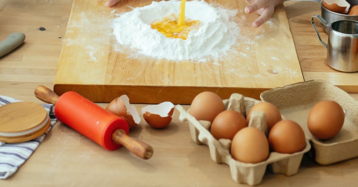 Why do you add the ingredients in sequences when stir frying? - Unrecognizable person mixing egg into flour at table with wooden board rolling pin and kitchenware in light kitchen while cooking