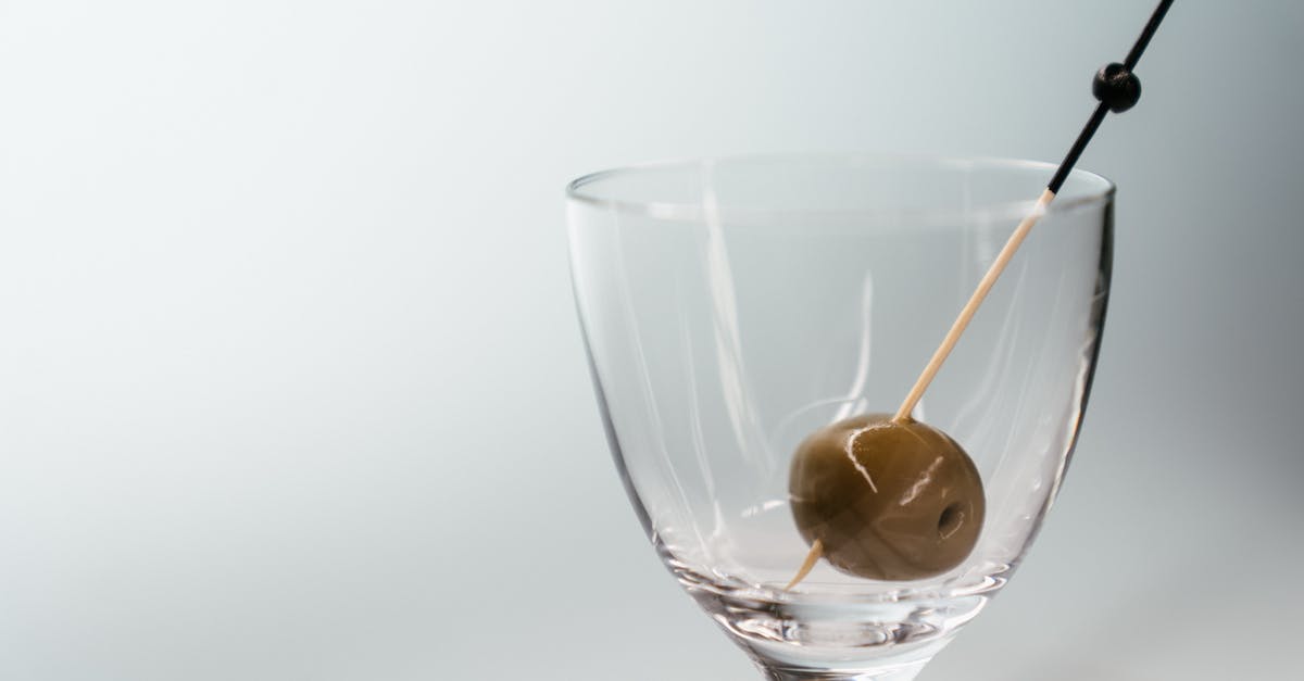 Why does a (vodka) martini often come with an olive on a stick? - Clear Wine Glass With Yellow Liquid