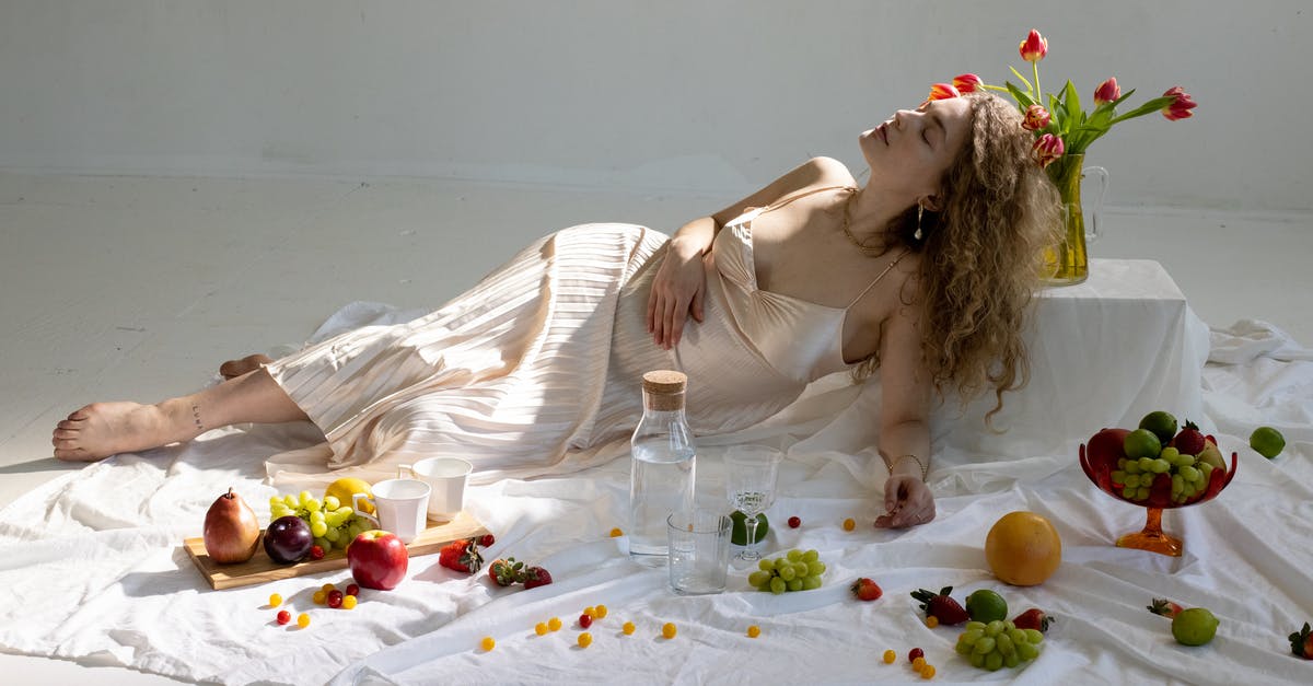 Why does canned mango pulp have no vitamin A? - Peaceful young elegant woman lying on floor near fruits scattered on white cloth
