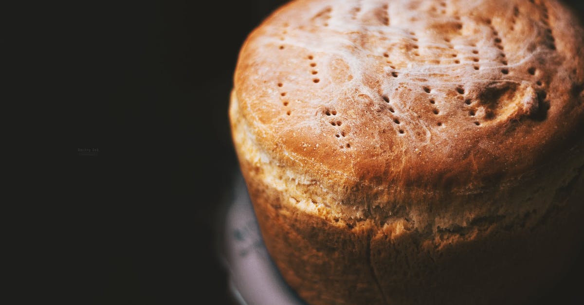Why does commercial brown (whole wheat) bread taste bitter? - From above of delicious homemade fresh baked loaf of bread with patterns on top served on plate on blurred black background