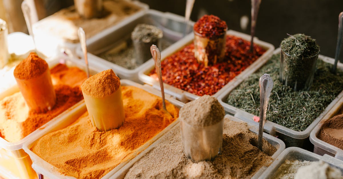 Why does curry flavor improve overnight (beyond the effects of permeation and infusion)? - Assorted spices at counter in street market