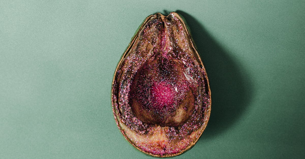 Why does food spoil in the freezer? - From above of half of rotten avocado covered with pink glitter placed on green background in studio