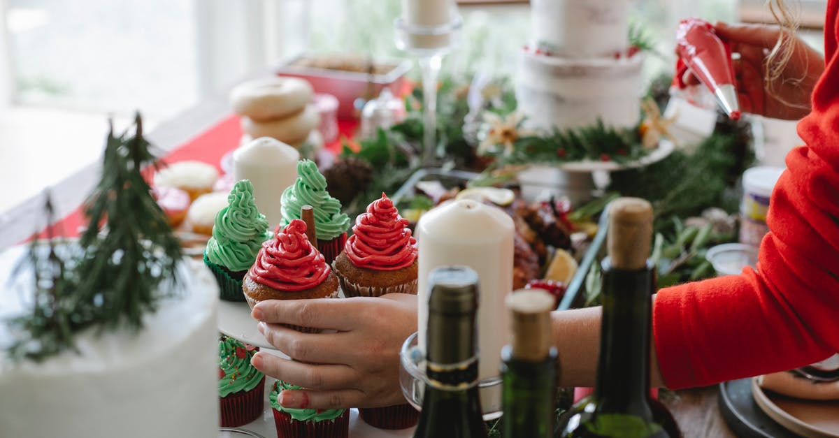 Why does my buttercream become runny overnight? - Crop anonymous female chef with buttercream in pastry bag and yummy cupcakes at table with decor on Christmas day