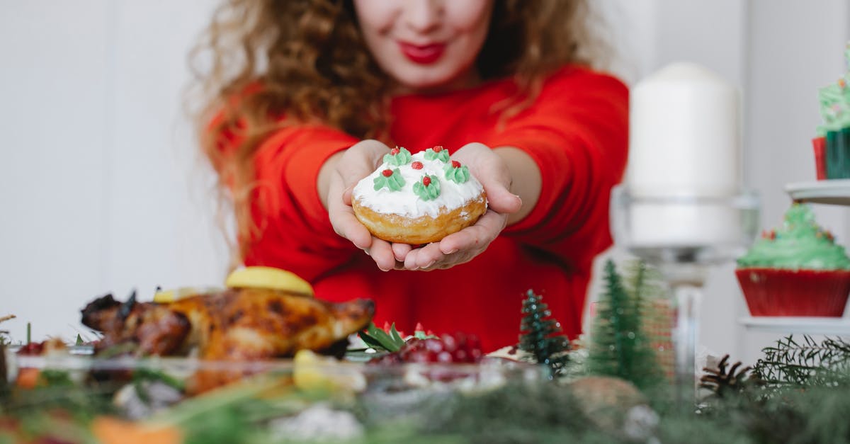 Why does my buttercream become runny overnight? - Crop woman showing tasty donut during New Year holiday indoors