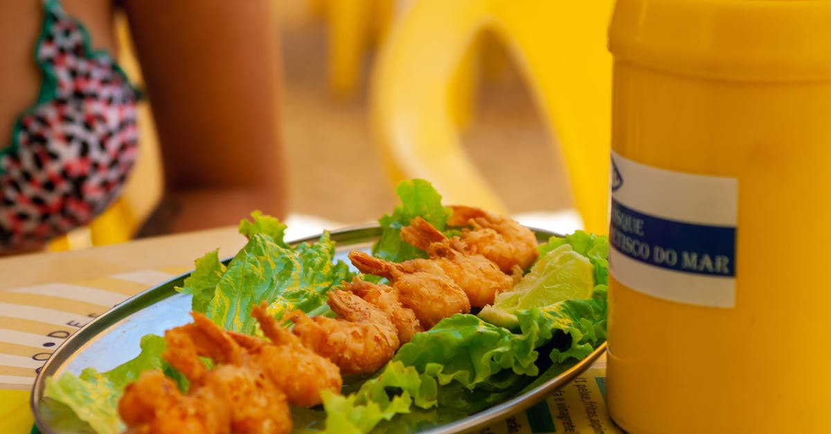 Why does the shrimp stick to the shells? - Faceless woman in swimwear eating shrimp tempura on long thin wooden stick on light green leaf of lettuce in outdoor cafe in summertime