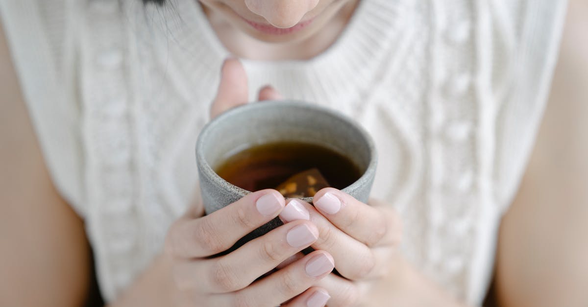 Why does this homemade herbal tea always boil over? - High angle of crop female smelling aromatic freshly brewed tea in ceramic cup