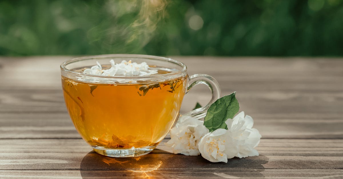 Why does this homemade herbal tea always boil over? - Glass cup of healthy herbal tea served on wooden table near fresh gentle Arabian jasmine flowers on sunny day on terrace