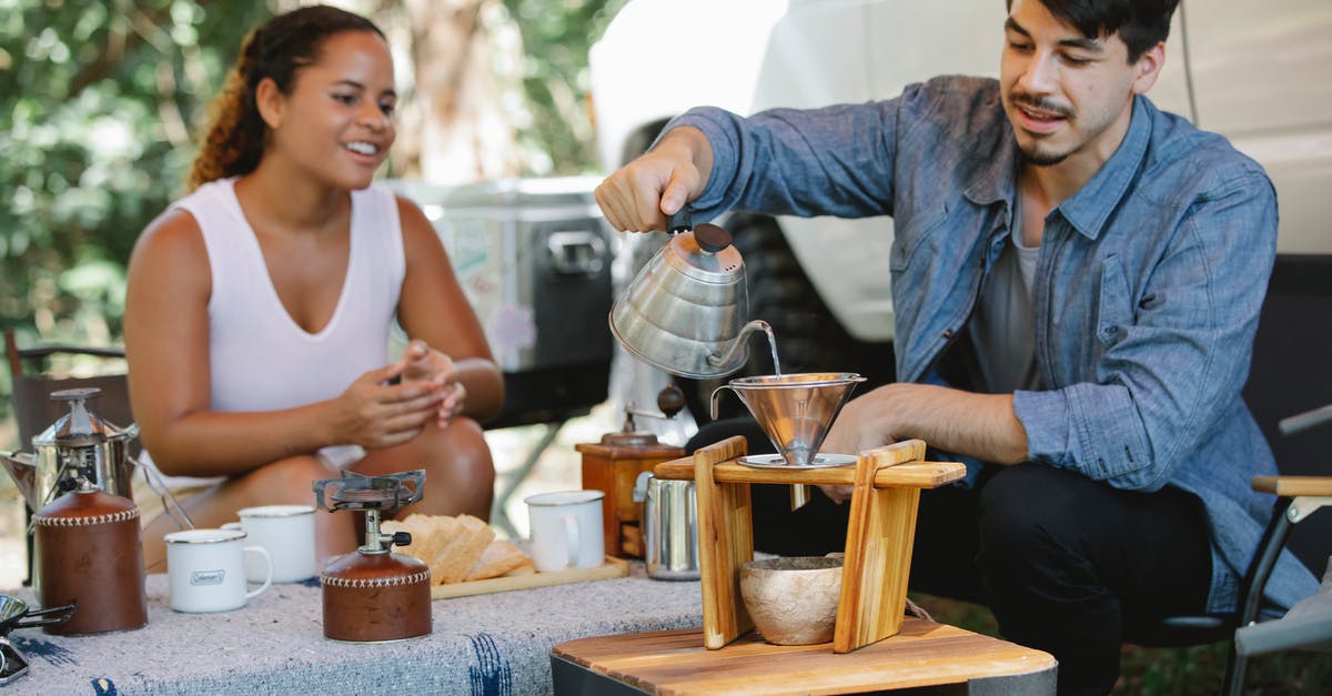 Why does water always boil over when steaming shrimp? - Content young man pouring hot water from gooseneck kettle into filter while preparing pour over coffee with smiling girlfriend during picnic