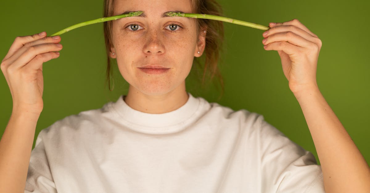 Why doesn't deep frying 'wet' the food? - Crop woman with fresh asparagus stems on green background