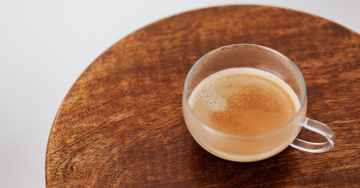 Why don't the single serve coffee cream cups need to be refrigerated? - From above of coffee with thin froth in glass cup placed on small round wooden table on white background Why don't the single serve coffee cream cups need to be refrigerated? - From above of coffee with thin froth in glass cup placed on small round wooden table on white background