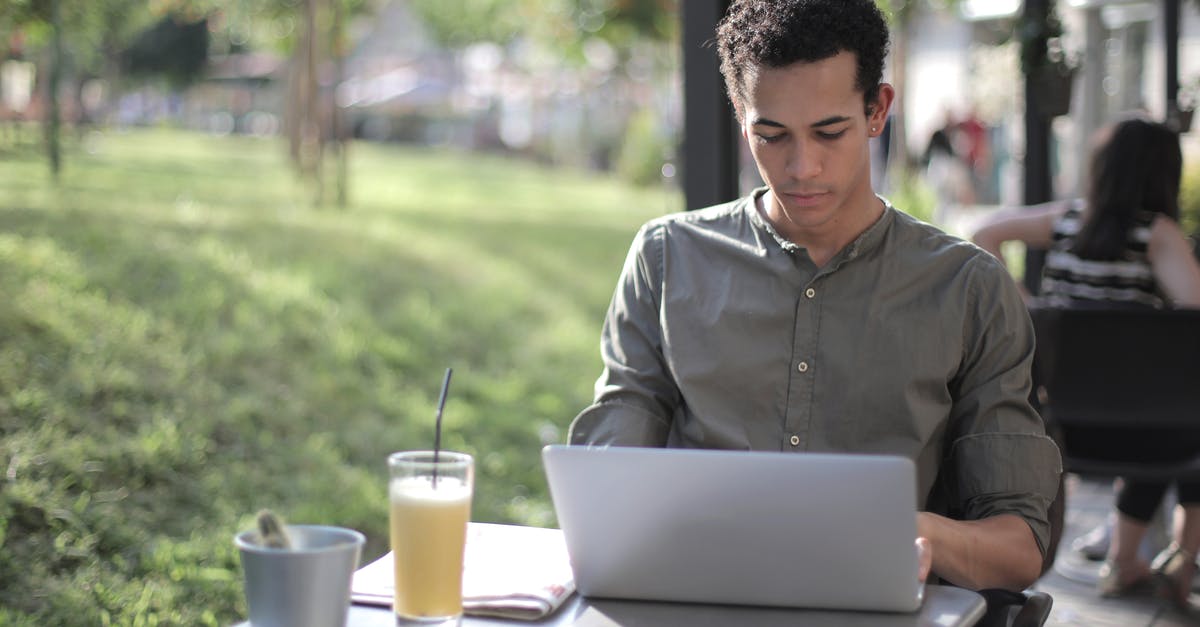 Why is black tea sold in crumbled form? - Focused black male freelancer using laptop in street cafe