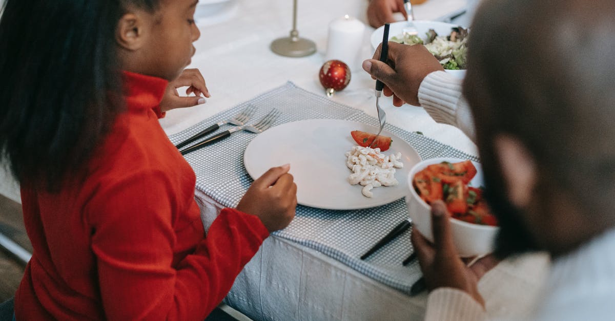 Why is my macaroni salad absorbing all the liquid? - From above of crop anonymous ethnic parent serving pasta salad and tomato slice to girl while celebrating New Year at home