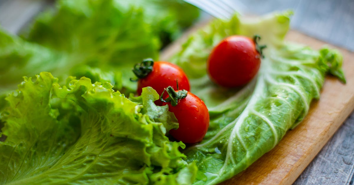 Why is my pickled red cabbage so pale? - Green salad leaves and ripe tomatoes on wooden cutting board