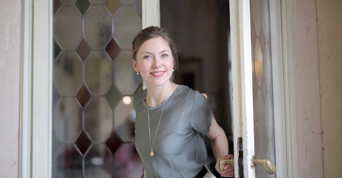 Why isn't glass ideal for the fermentation of sauerkraut? - Young smiling female in casual outfit looking at camera and holding on doorknob while entering through stained glass vintage door in ancient building