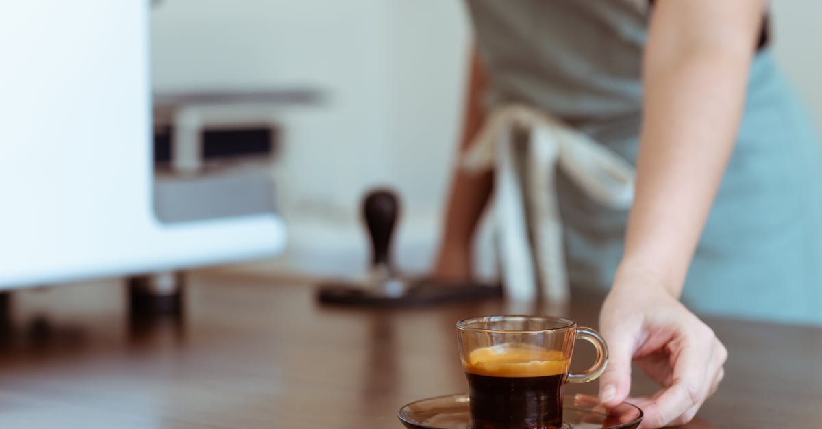 Why isn't my espresso coffee nice and strong? - Crop coffee house worker serving cup of freshly brewed espresso