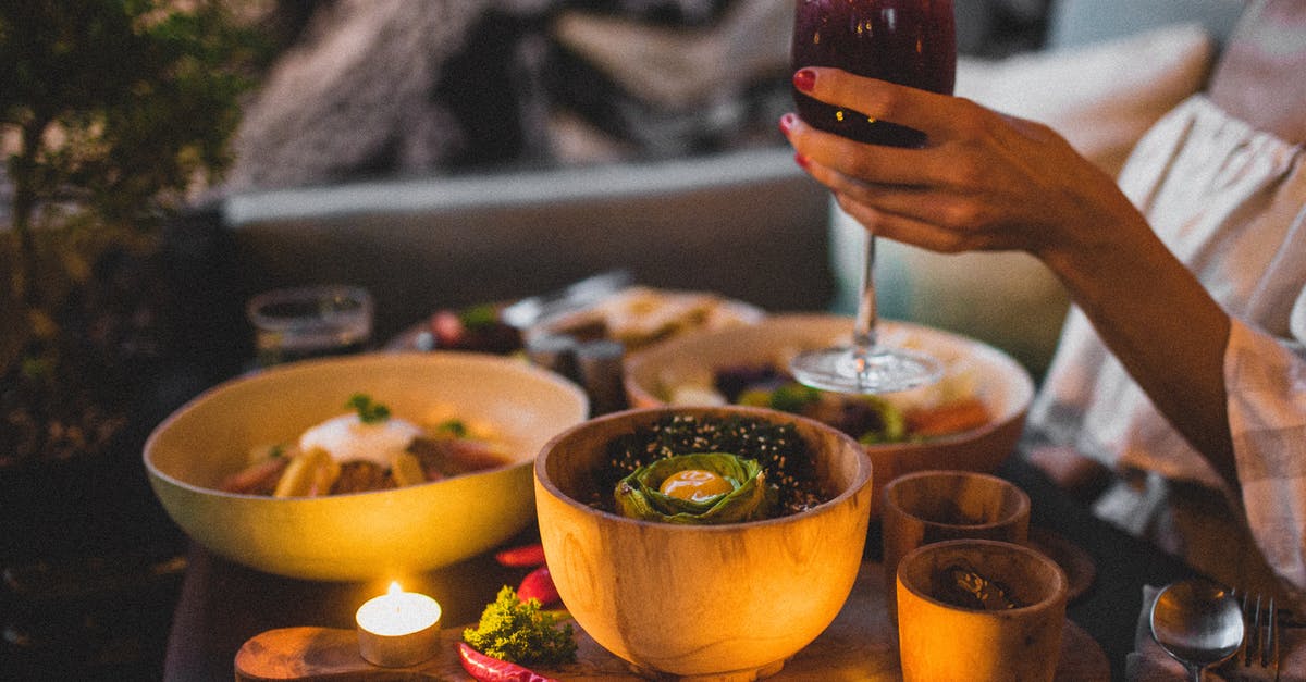 Why mixing hot syrup (sugar + water) into yolks in sabayon? - Crop anonymous pregnant female holding glass of red wine while standing near table with lentil dish and salad near hot chili pepper and candles in evening