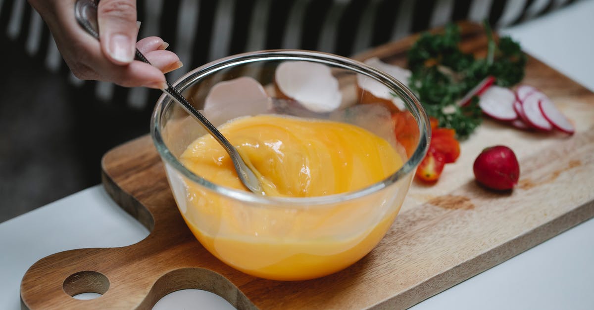 Why or why not beat an egg before adding? - High angle of crop female beating eggs in glass bowl standing at table with ingredients for breakfast on cutting board