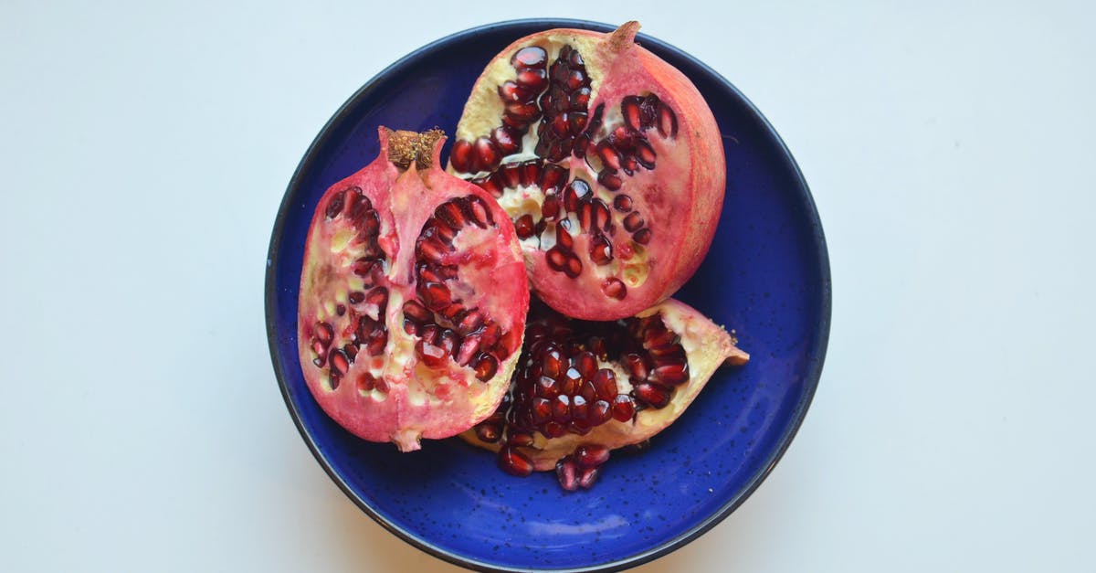 why pepitas (pumpkin seeds) taste like blue cheese? - Top view of fresh ripe halves of pomegranate with red seeds in bowl placed on white background in light kitchen