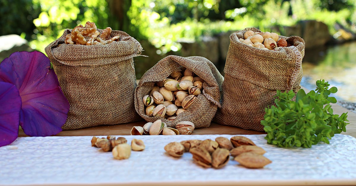 Why the overlap in peanut and tree nut allergies? - Jute sacks with pistachios walnuts and peanuts placed on wooden table in park near pond on sunny day