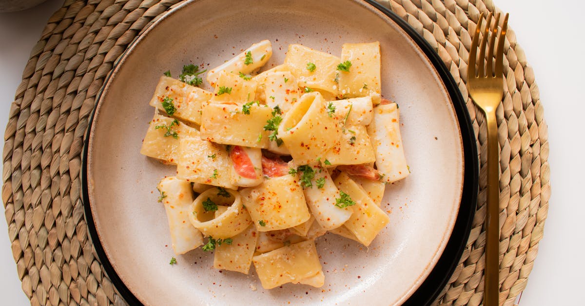 Why use chopped tomatoes and tomato paste/puree? - From above of juicy pasta with tiny slices of tomato and chopped parsley with ground black pepper on round plate near fork on straw mat