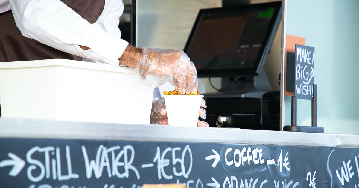 why won't my lentils cook uniformly? - Low angle of crop anonymous male seller with cup of fried food at counter with cashier