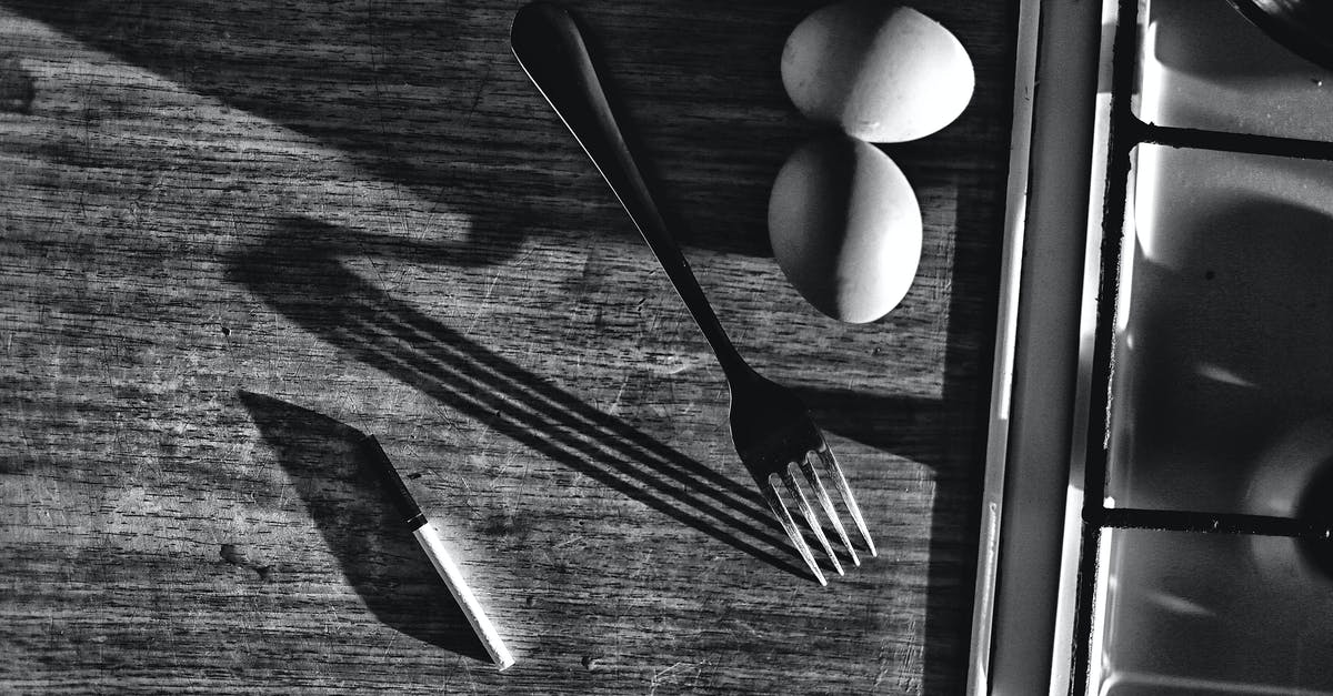 Why would I prefer carbon steel (rust prone) kitchen knife? - Black and white top view of chicken eggs with fork and knife on table with shades against sink at home