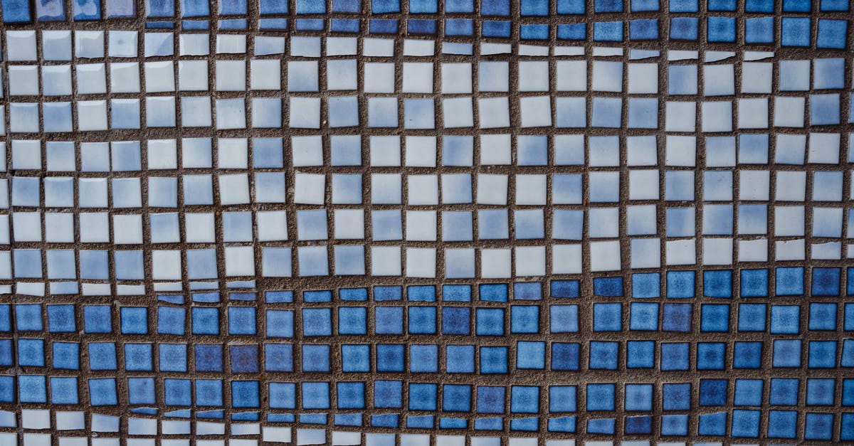 Why would milk form a dense emulsion when warmed? - Textured ceramic square shaped white and blue tile of wall of old building