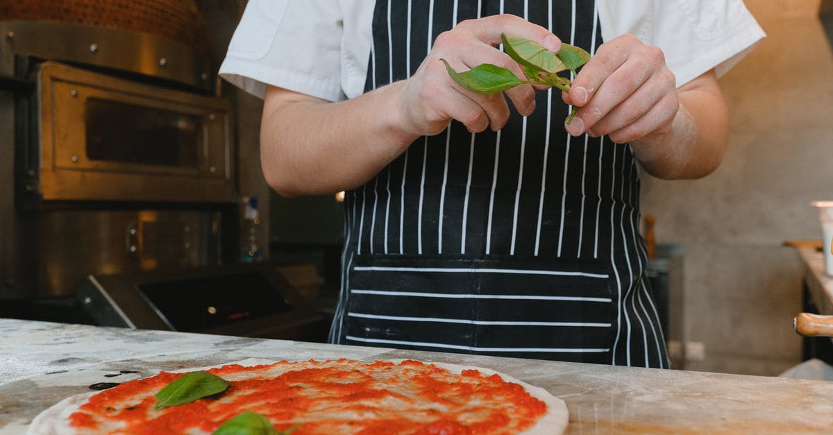 Working with sticky dough for pizza making - Man Making a Pizza and Holding Green Leaves