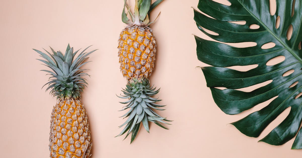 Would freezing a whole pineapple change it visually? - From above whole sweet yummy pineapples and big green tropical leaf on beige background