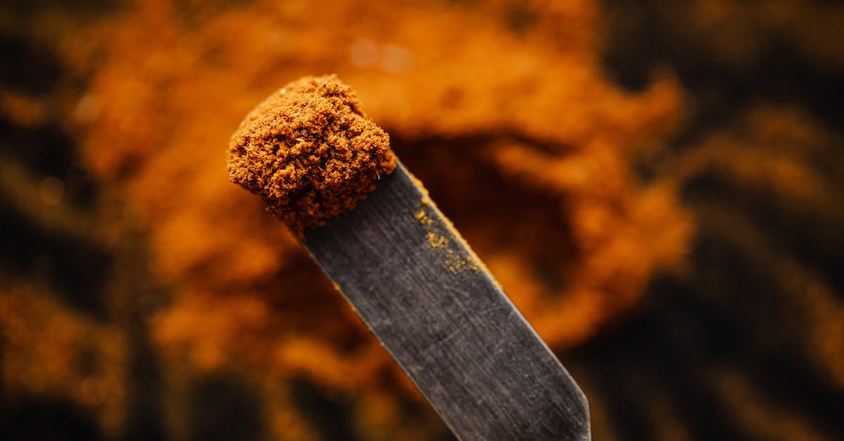 Would ground "popcorn meal" differ from regular corn meal? - Closeup spatula with sample of ground paprika taken from heap in dark barn