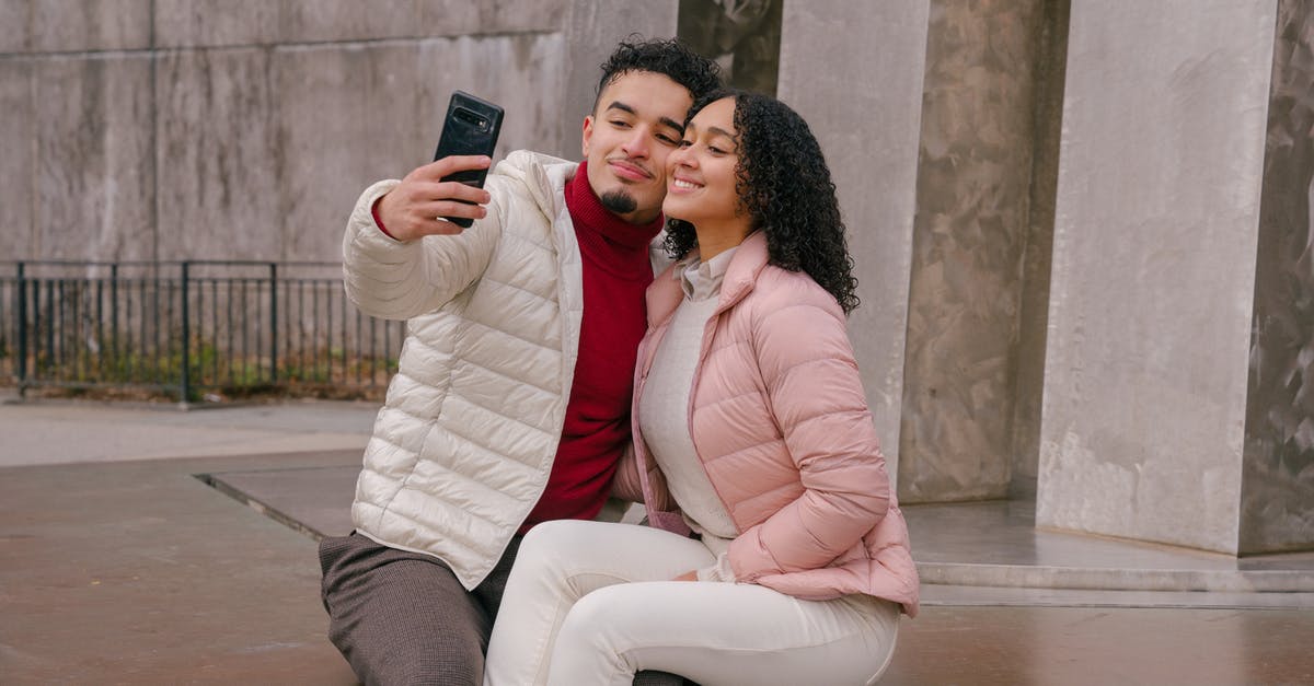 Yoghurt after use by date [duplicate] - Delighted young ethnic couple touching cheeks while taking selfie sitting on parapet