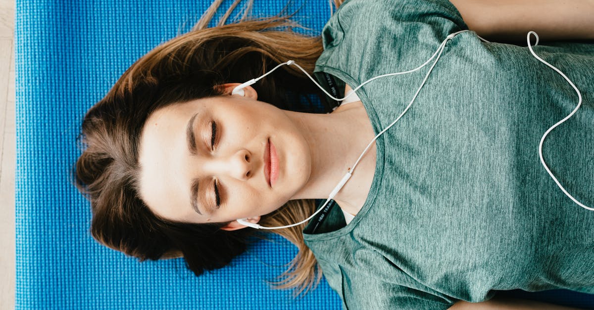 Yolks flat and breaking - Tranquil woman resting on yoga mat in earphones at home