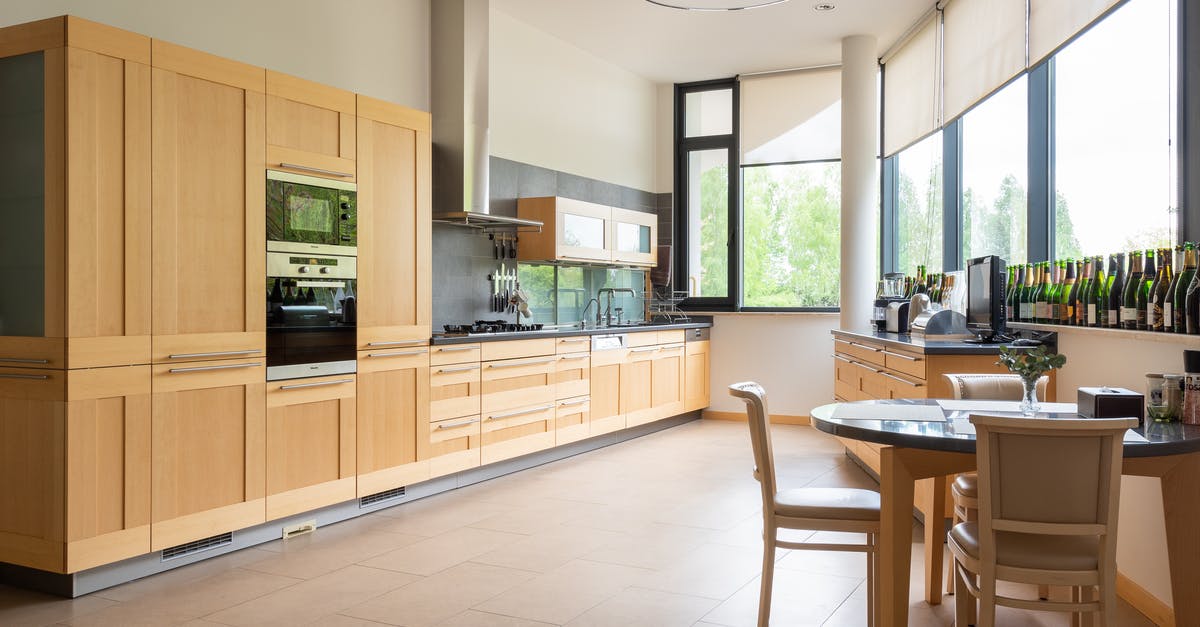 Yorkshire puddings in a fan assisted oven - Table with chairs placed near wooden cupboards and modern kitchenware in light spacious kitchen with collection of bottles near window